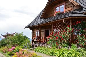 a wooden house with flowers in front of it at Góralska Ostoja - tradycyjny, drewniany dom na Kudłaczach, duży ogród, piękna panorama, sauna, jacuzzi in Pcim