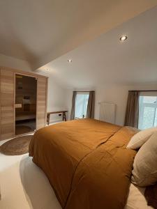 - une chambre avec un grand lit et une couverture orange dans l'établissement L'Officine - Résidence Le Cercle, à Marche-en-Famenne