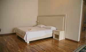 a bedroom with a white bed and a wooden floor at Hotel Lux in Makhachkala