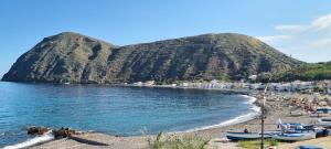 a beach with boats on the water and a mountain at La casa sul mare in Lipari
