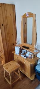 a wooden dresser with a mirror and a stool at Guest House Edelweiss in Govedartsi