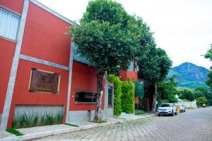 a red building with a car parked next to a street at Pousada Jeito de Minas in Governador Valadares