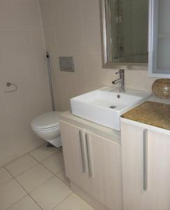 een witte badkamer met een wastafel en een toilet bij Ocean Breeze 23 in Kingsborough