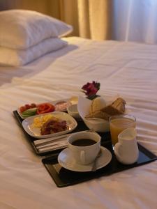 a tray of food on a bed with a cup of coffee at LA Hotel in Lidingö