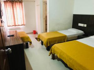 a room with two beds with yellow covers on them at Star Residency in Mysore