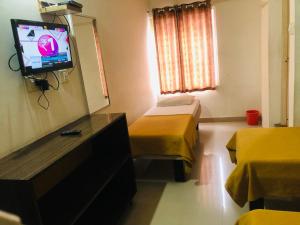 a room with two beds and a flat screen tv at Star Residency in Mysore