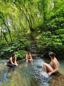 tres personas sentadas en el agua en un río en Sarinbuana Eco Lodge, en Blimbing