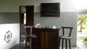a bar with two bar stools and a television at Sitio Santo Antonio HOSTEL in Ilhéus