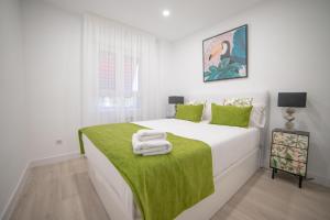 biała sypialnia z łóżkiem z zielonym kocem w obiekcie Apartment IFEMA-Mar de Cristal II w Madrycie