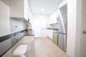 Biała kuchnia z białymi blatami i urządzeniami w obiekcie Apartment IFEMA-Mar de Cristal II w Madrycie