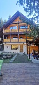 a building with a person sitting on a bench in front of it at Cabana "Trei Brazi " Retezat in Rîu de Mori