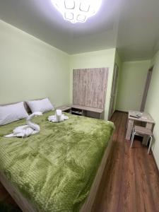 a bedroom with a large bed with a green blanket at Готель ТІК Копичинці in Sukhostav