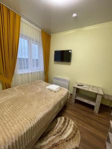 a bedroom with a bed and a table and a tv at Готель ТІК Копичинці in Sukhostav