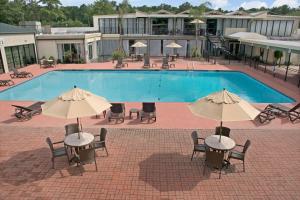 a pool with tables and chairs and umbrellas at Ramada by Wyndham Houston Intercontinental Airport East in Humble
