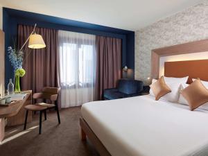 パリにあるノボテル パリ レ アールの大きなベッドとデスクが備わるホテルルームです。