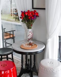 a table with a vase with red flowers on it at The Lantern Hatyai Hotel in Hat Yai