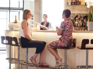 two women sitting on bar stools at a counter at Novotel Suites Reims Centre in Reims