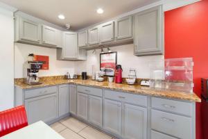 una cocina con armarios blancos y una pared roja en Econo Lodge, en Goose Creek