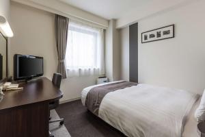 a hotel room with a bed and a desk with a television at Comfort Hotel Akita in Akita