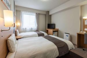 a hotel room with two beds and a television at Comfort Hotel Akita in Akita