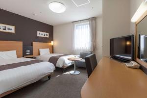 a hotel room with two beds and a flat screen tv at Comfort Hotel Sendai West in Sendai