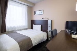 a hotel room with a bed and a desk and a television at Comfort Hotel Tsubamesanjo in Sanjo