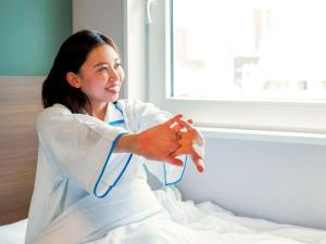 a woman in a white lab coat sitting on a bed at Comfort Hotel Nara in Nara