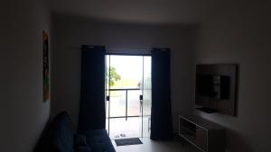 un soggiorno con porta scorrevole in vetro e TV di AbeQuar apartamentos beira-mar para temporada a Itanhaém