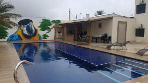 uma piscina com um mural ao lado de uma casa em AbeQuar apartamentos beira-mar para temporada em Itanhaém