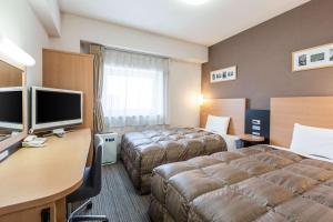 Habitación de hotel con 2 camas y escritorio en Comfort Hotel Kurosaki, en Kitakyushu