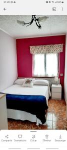 una camera con un grande letto con una parete rossa di Apartamento en San Juan de L'arena a San Juan de la Arena