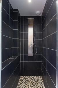 baño con ducha de azulejos negros en Dune et Coquelicot, en Gaillan-en-Médoc
