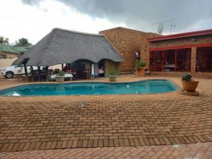 a small swimming pool with a building with a roof at Die Rooi Windpomp in Polokwane