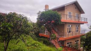 a building on the side of a hill with trees at Blue Mountain Village Cottage in Nainital