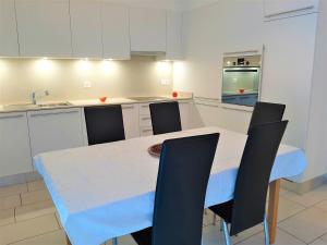 una cucina con tavolo bianco e sedie nere di San Giulio Roveredo a Roveredo