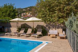 a swimming pool with lounge chairs and umbrellas next to at Grappolo Lefkada Villas - Athiri, 5 min from wonderful Ai Giannis beach & Lefkada town in Apolpaina