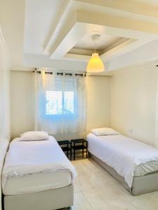 two beds in a room with white walls and a ceiling at Royal Beach Front Apartments in Netanya