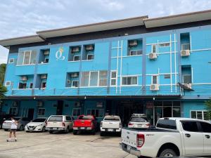 a blue building with cars parked in a parking lot at ควีนเพลส สระบุรี Queenplace Saraburi in Sara Buri