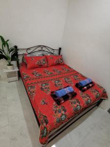 a bed with a red comforter and two pillows at LYNN HOMESTAY SERI ISKANDAR in Seri Iskandar
