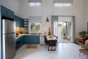 a kitchen with blue cabinets and a table with chairs at Grappolo Lefkada Villas - Athiri, 5 min from wonderful Ai Giannis beach & Lefkada town in Apolpaina