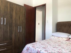 a bedroom with a bed and a wooden cabinet at Residencial De Aluguel in Bombinhas
