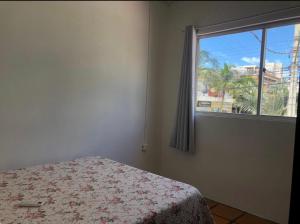 a bedroom with a bed and a window with a view at Residencial De Aluguel in Bombinhas