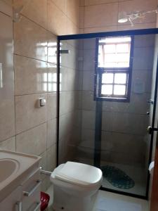 a bathroom with a toilet and a shower with a window at kit net montanha das letras in São Thomé das Letras