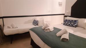 duas camas num quarto com toalhas em Hostal Hom Museo em Sevilha