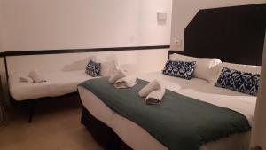 a hotel room with two beds and a couch at Hostal Hom Museo in Seville