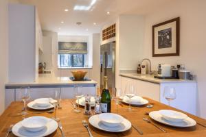 a kitchen with a wooden table with plates and wine glasses at 8 Pen y Bont in Abersoch