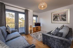 a living room with two couches and a sliding glass door at 8 Pen y Bont in Abersoch