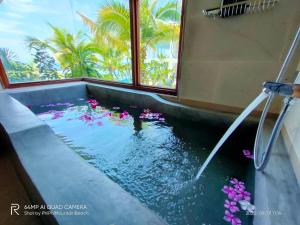 a bathtub with a pool of water with pink flowers in it at PP Mountain Beach Resort in Phi Phi Islands