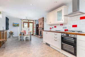 a kitchen with white cabinets and a table in it at The Pigsty - 3 Bedroom Barn Conversion in Coventry