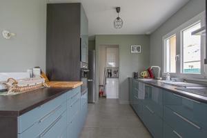 Una cocina con gabinetes azules y una encimera. en La maison des marronniers, en Bayeux 7 fotos más